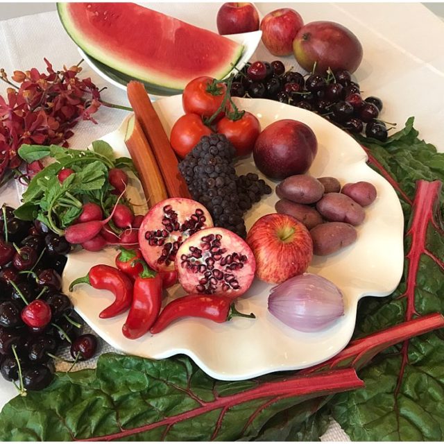 Assorted display of red foods including pomegranates, cherries, peppers and watermelon